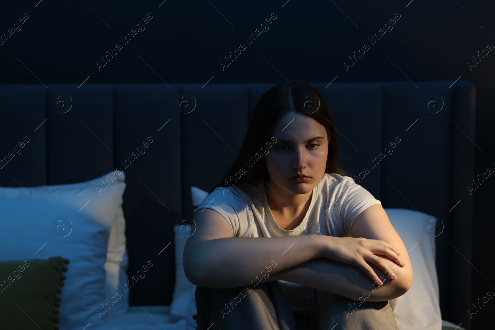 Sad young woman sitting on bed at home Photo of Sad young woman sitting on bed at home