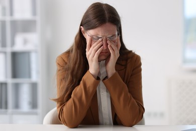Photo of Sad young woman at white table in office