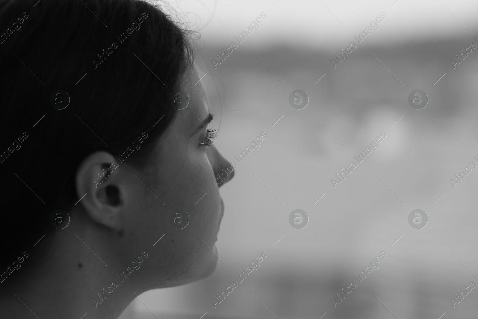 Sad young woman near window at home, closeup and space for text. Black and white effect Photo of Sad young woman near window at home, closeup and space for text. Black and white effect