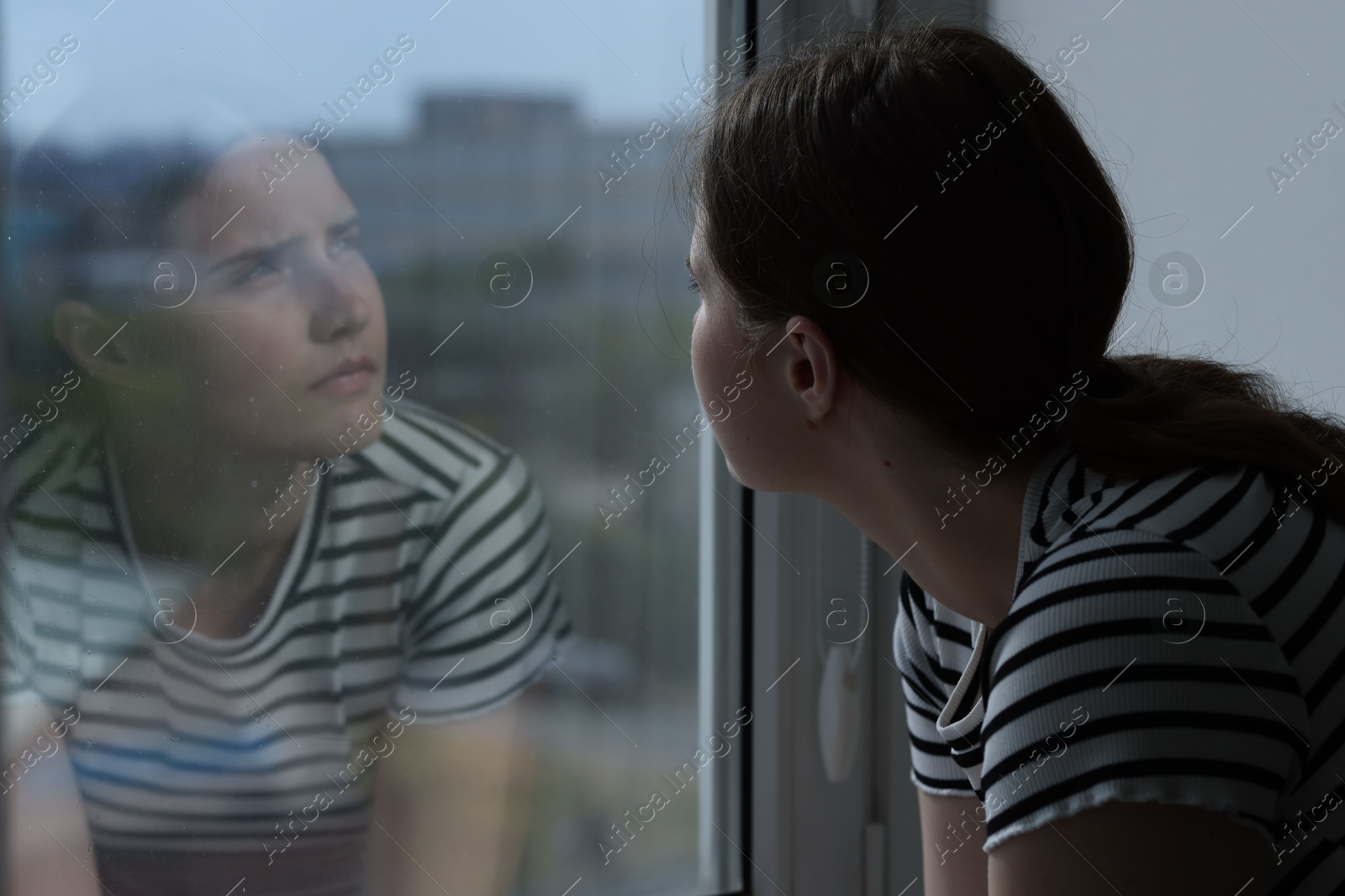 Photo of Sad young woman near window at home, space for text