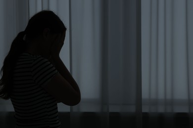 Photo of Silhouette of sad young woman at home. space for text