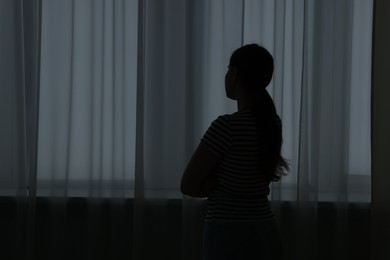Photo of Silhouette of sad young woman at home. space for text