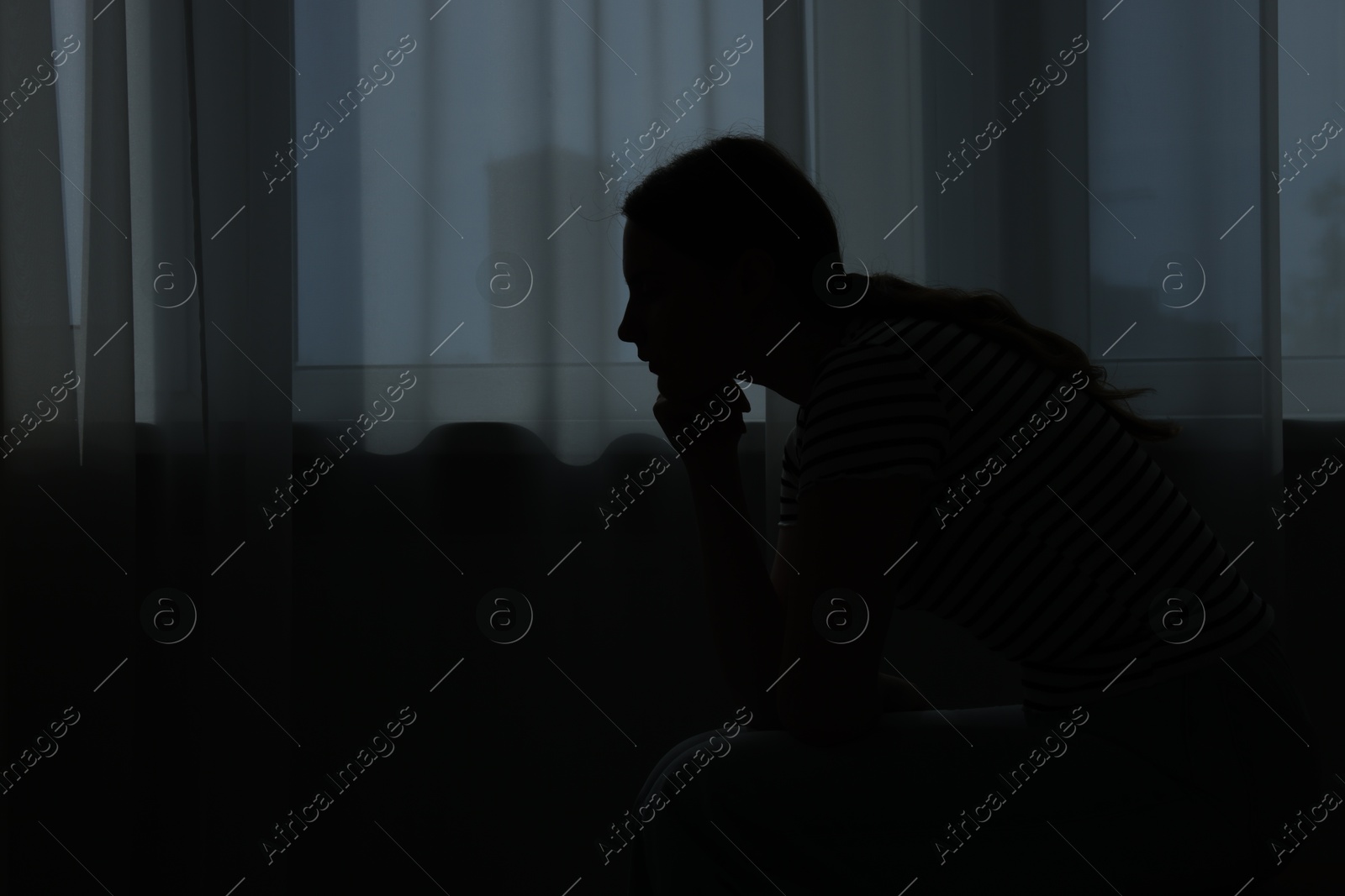 Photo of Silhouette of sad young woman at home. space for text