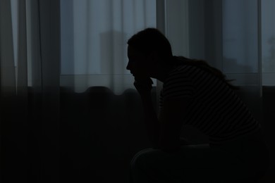 Photo of Silhouette of sad young woman at home. space for text