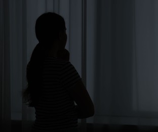 Photo of Silhouette of sad young woman at home. space for text