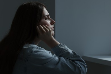 Photo of Sad young woman near grey wall indoors