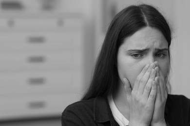 Photo of Sad young woman at home, space for text. Black and white effect