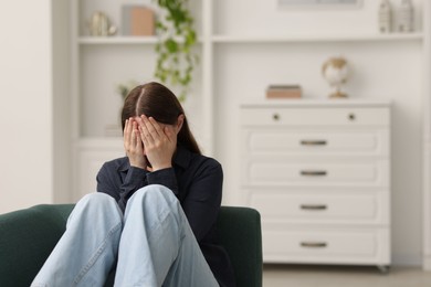 Photo of Sad young woman crying on sofa at home, space for text