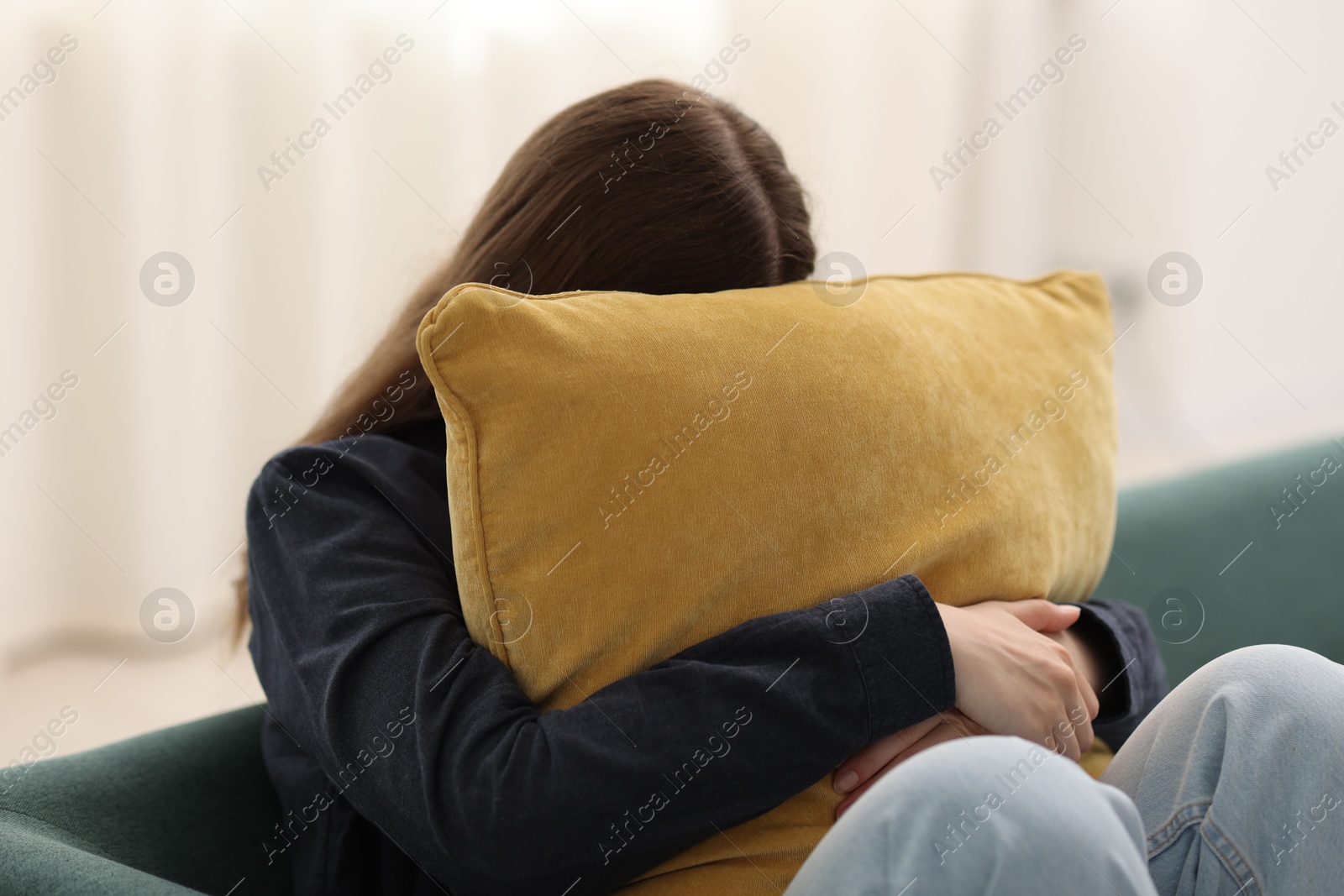 Sad young woman with pillow sitting on sofa at home Photo of Sad young woman with pillow sitting on sofa at home