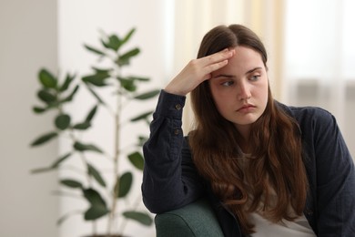Photo of Sad young woman sitting on sofa at home, space for text