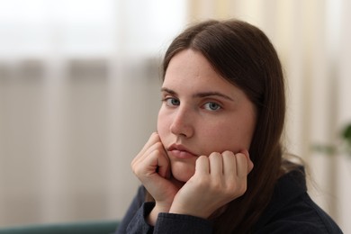Photo of Sad young woman at home, space for text