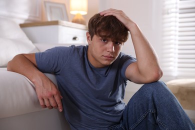 Photo of Teenage boy suffering from panic near sofa at home
