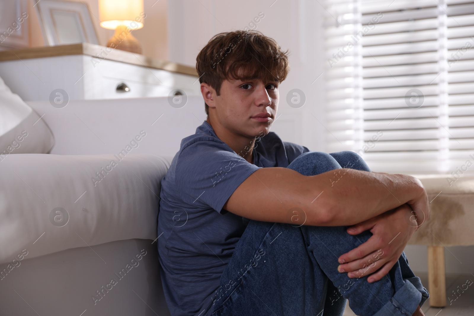 Photo of Teenage boy suffering from panic near sofa at home