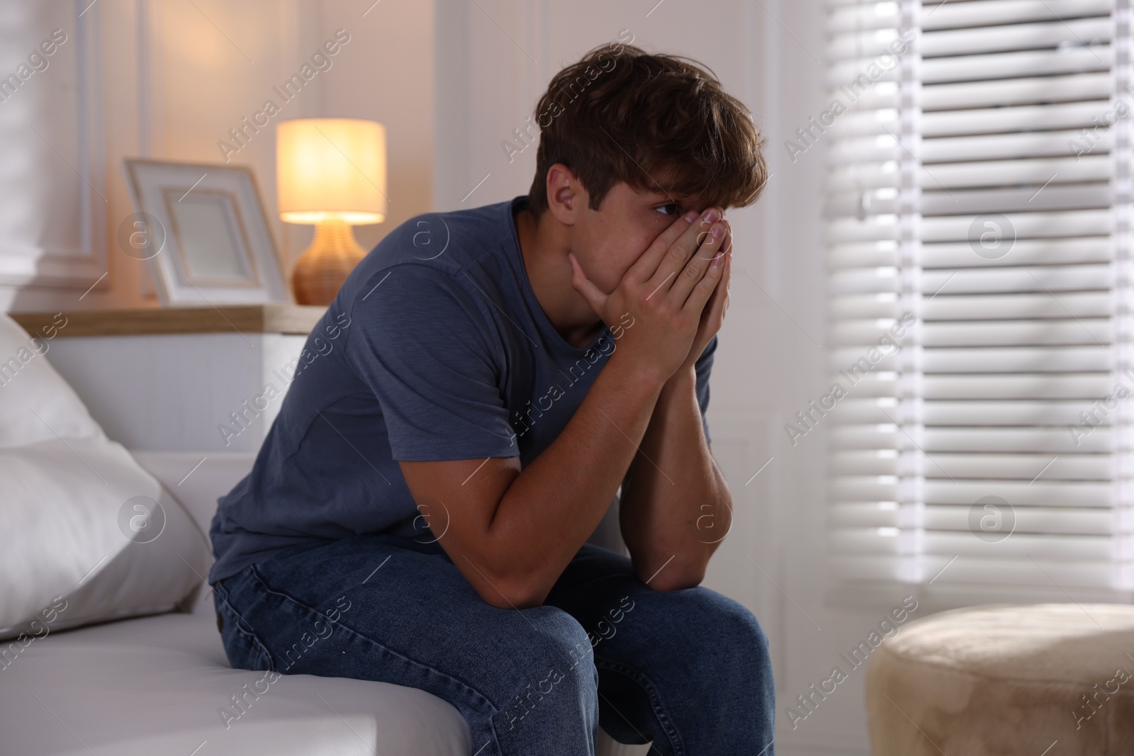 Photo of Teenage boy suffering from panic attack on sofa at home