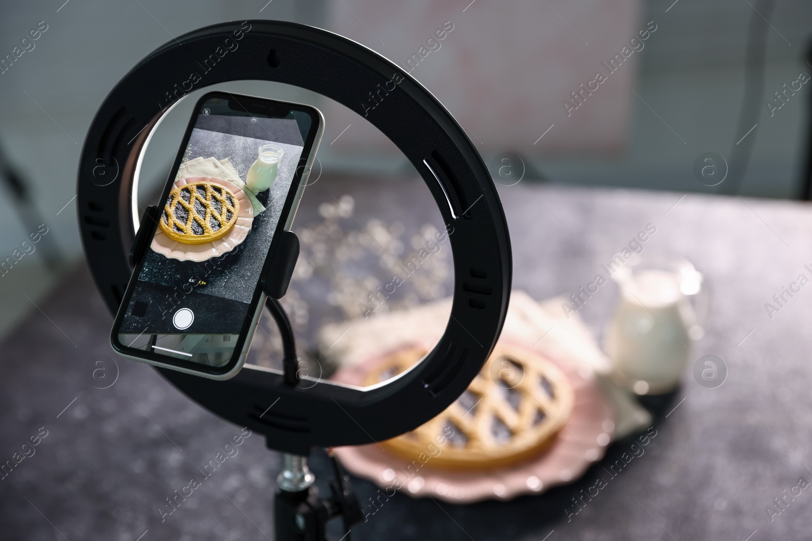 Photo of Shooting tasty pie and milk with smartphone in studio, selective focus. Professional food photography