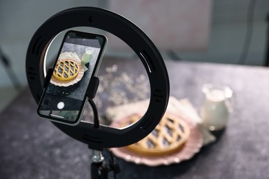Photo of Shooting tasty pie and milk with smartphone in studio, selective focus. Professional food photography