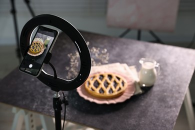 Photo of Shooting tasty pie and milk with smartphone in studio, selective focus. Professional food photography