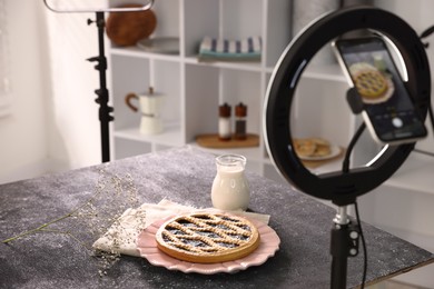 Photo of Shooting tasty pie and milk with smartphone in studio, selective focus. Professional food photography