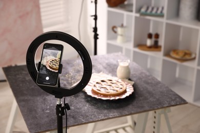 Photo of Shooting tasty pie and milk with smartphone in studio, selective focus. Professional food photography