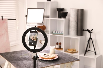 Photo of Shooting tasty pie and milk with smartphone in studio, selective focus. Professional food photography