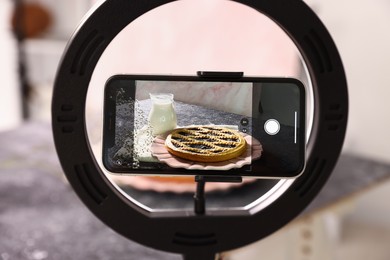 Photo of Shooting tasty pie and milk with smartphone in studio, selective focus. Professional food photography
