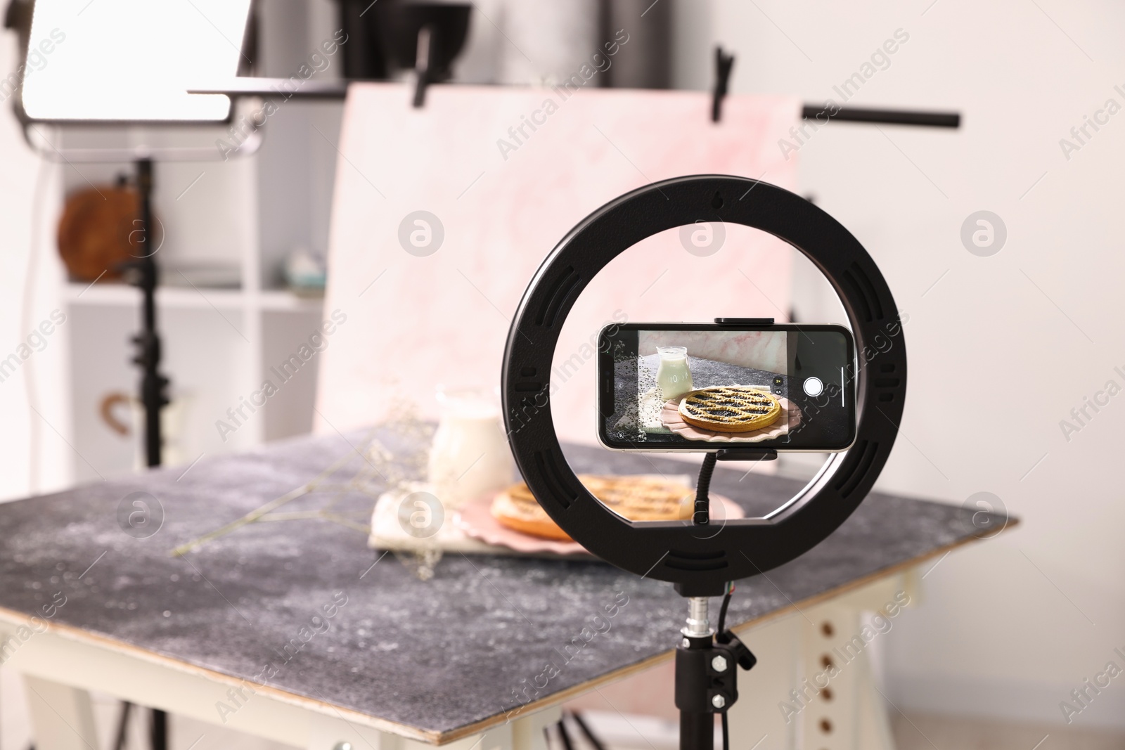 Photo of Shooting tasty pie and milk with smartphone in studio, selective focus. Professional food photography
