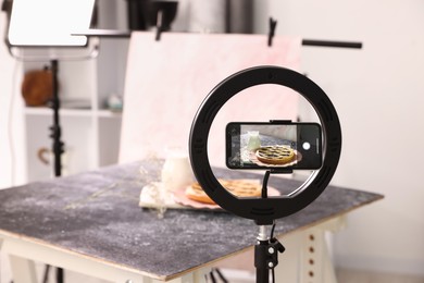 Photo of Shooting tasty pie and milk with smartphone in studio, selective focus. Professional food photography