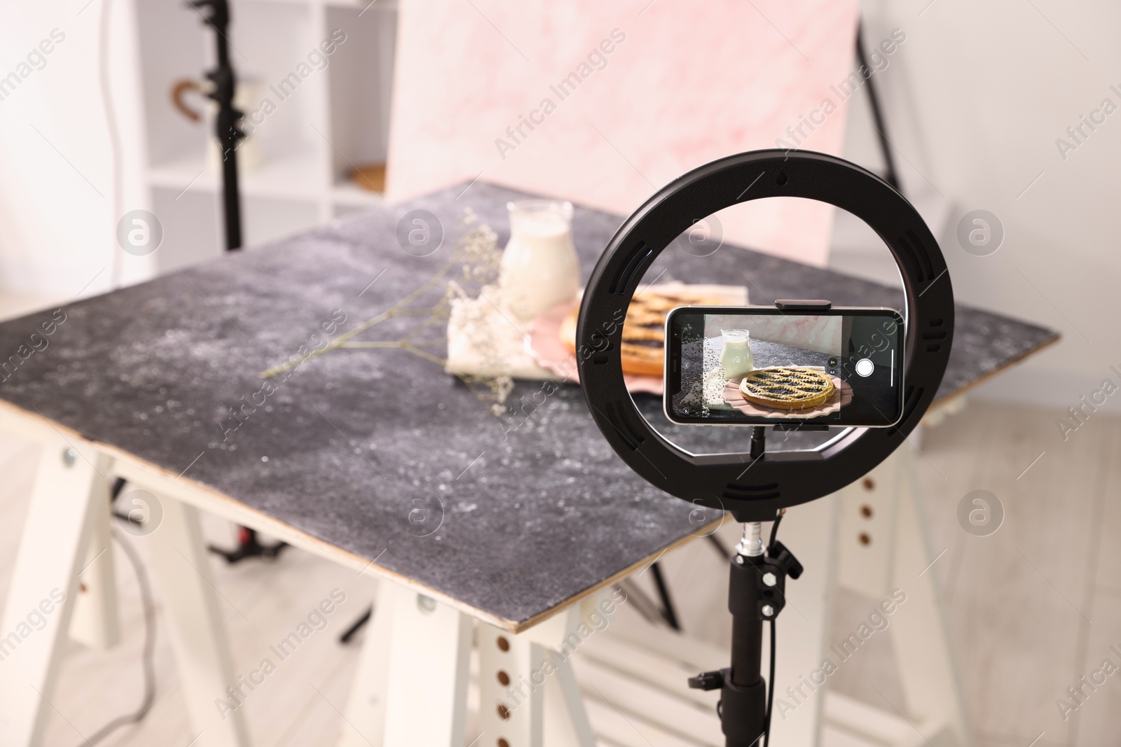 Photo of Shooting tasty pie and milk with smartphone in studio, selective focus. Professional food photography