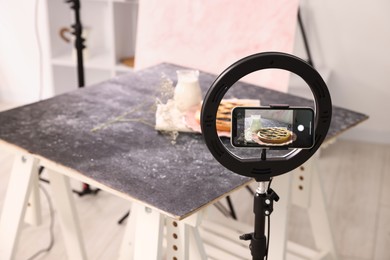 Photo of Shooting tasty pie and milk with smartphone in studio, selective focus. Professional food photography