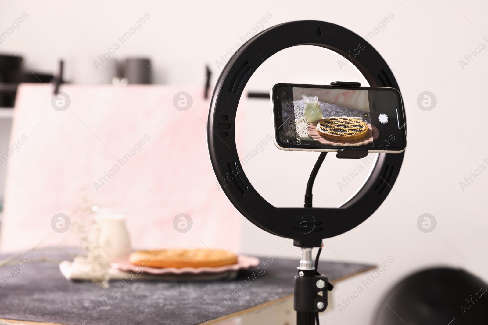Photo of Shooting tasty pie and milk with smartphone in studio, selective focus. Professional food photography