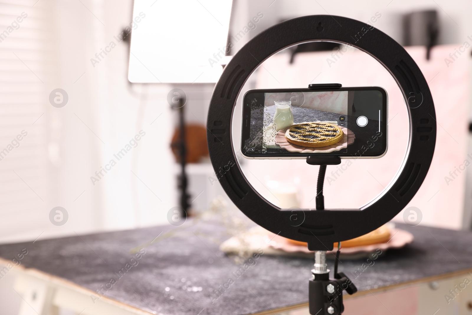 Photo of Shooting tasty pie and milk with smartphone in studio, selective focus. Professional food photography