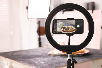 Photo of Shooting tasty pie and milk with smartphone in studio, selective focus. Professional food photography