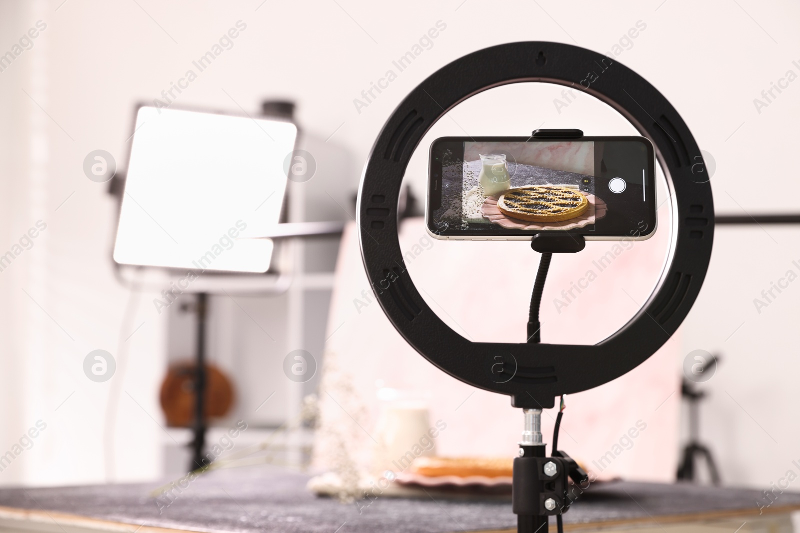 Photo of Shooting tasty pie and milk with smartphone in studio, selective focus. Professional food photography