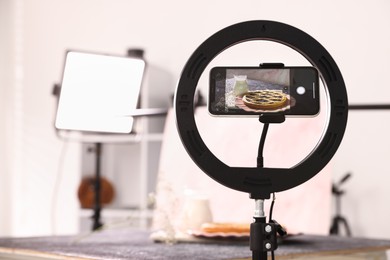 Photo of Shooting tasty pie and milk with smartphone in studio, selective focus. Professional food photography