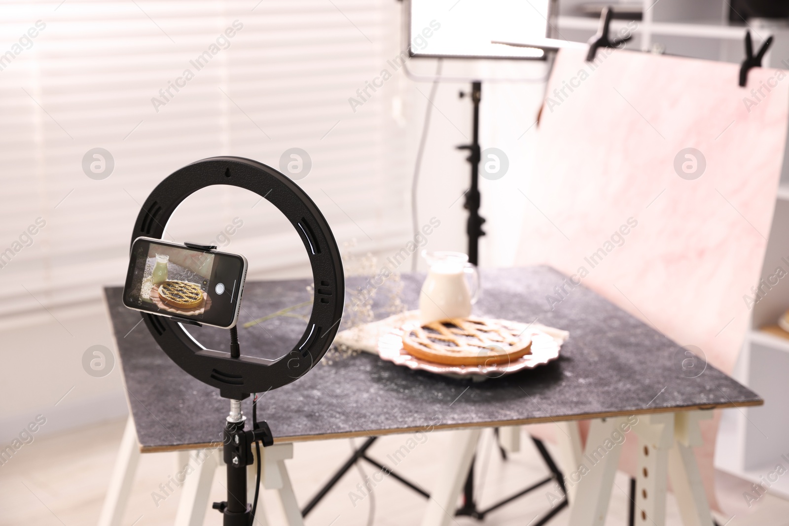 Photo of Shooting tasty pie and milk with smartphone in studio, selective focus. Professional food photography