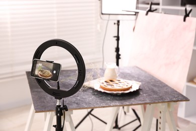 Photo of Shooting tasty pie and milk with smartphone in studio, selective focus. Professional food photography