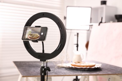 Photo of Shooting tasty pie and milk with smartphone in studio, selective focus. Professional food photography