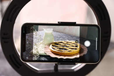 Photo of Shooting tasty pie and milk with smartphone in studio, selective focus. Professional food photography