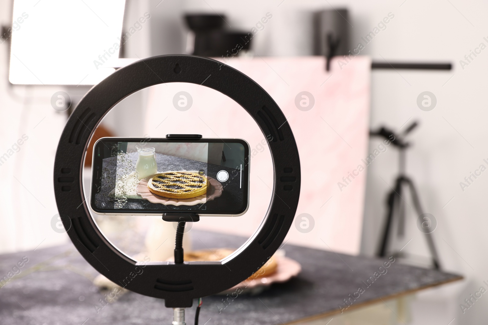 Photo of Shooting tasty pie and milk with smartphone in studio, selective focus. Professional food photography