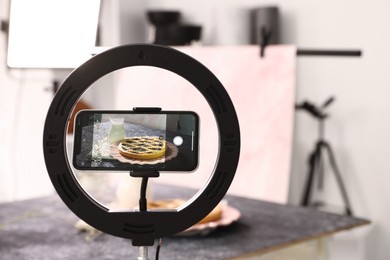 Photo of Shooting tasty pie and milk with smartphone in studio, selective focus. Professional food photography