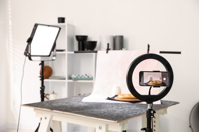 Photo of Shooting tasty pie and milk with smartphone in studio, selective focus. Professional food photography