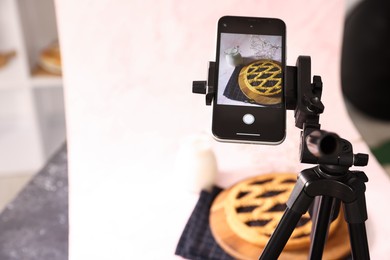 Photo of Shooting tasty pie and milk with smartphone in studio, selective focus. Professional food photography