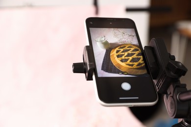 Photo of Shooting tasty pie and milk with smartphone in studio, selective focus. Professional food photography