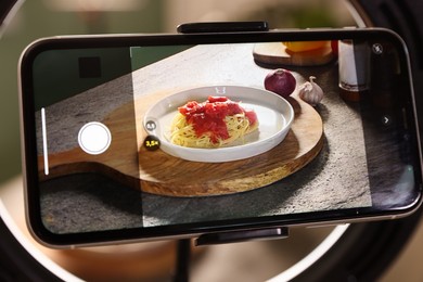 Photo of Shooting tasty pasta and ingredients with smartphone in studio, selective focus. Professional food photography