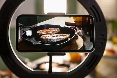 Photo of Shooting tasty roasted fish with smartphone in studio, selective focus. Professional food photography