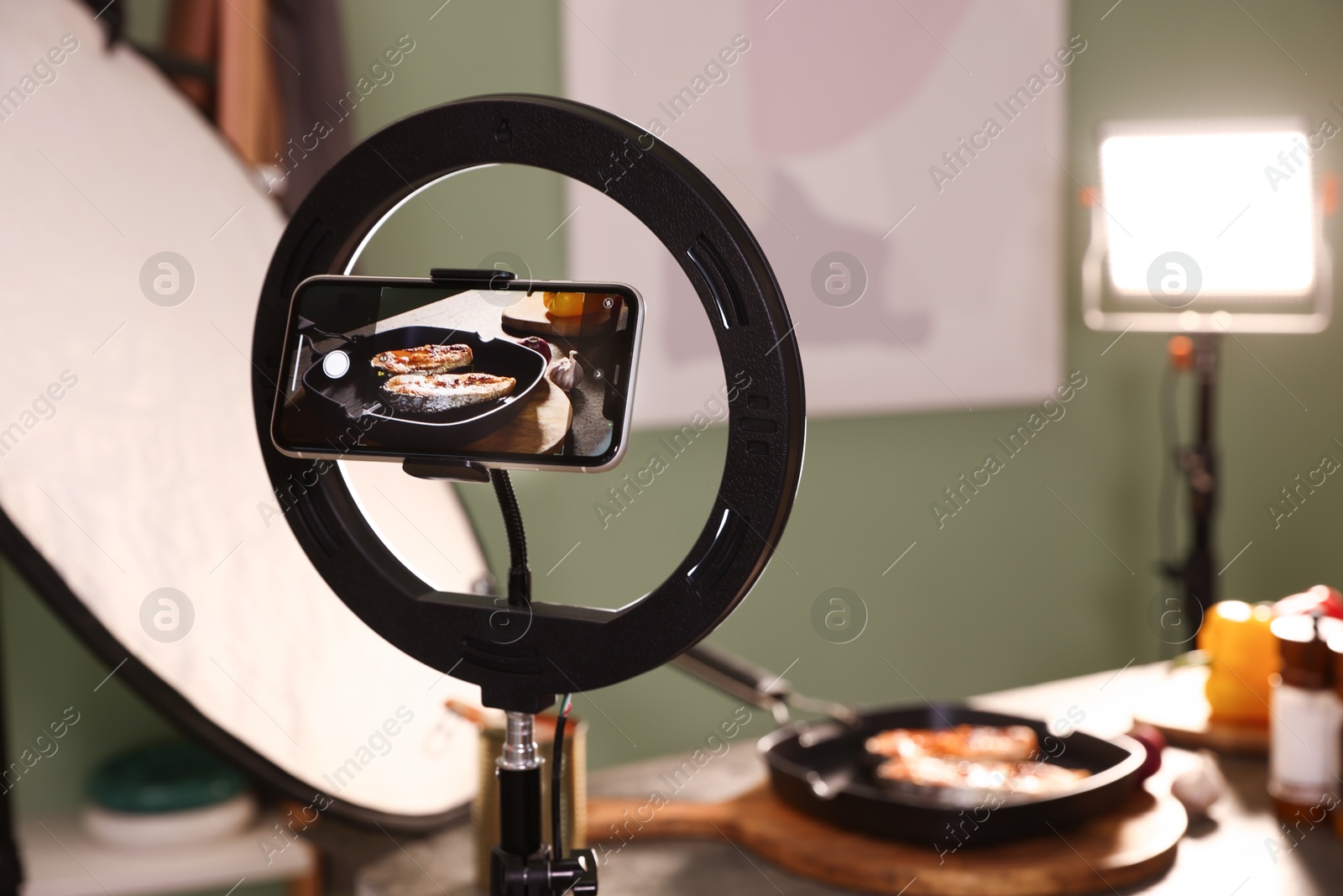 Photo of Shooting tasty roasted fish with smartphone in studio, selective focus. Professional food photography