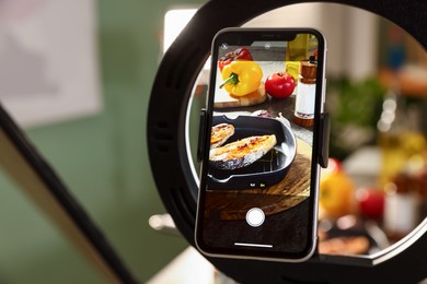 Photo of Shooting tasty roasted fish and ingredients with smartphone in studio, selective focus. Professional food photography
