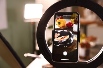 Photo of Shooting tasty roasted fish and ingredients with smartphone in studio, selective focus. Professional food photography