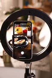 Photo of Shooting tasty roasted fish and ingredients with smartphone in studio, selective focus. Professional food photography