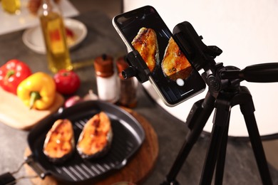 Photo of Shooting tasty roasted fish with smartphone in studio, selective focus. Professional food photography